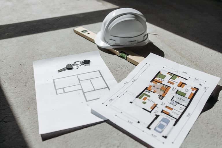 Construction blueprints and building permit documents with hard hat for Arizona survey checklist